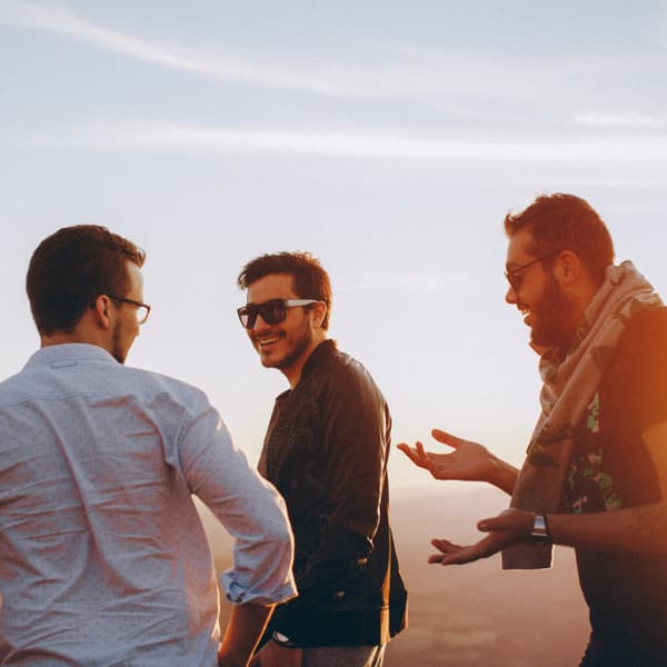 Friends talking by the water at sunset